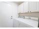 Clean laundry room with white appliances and built-in storage cabinets above the washer and dryer at 17293 N Ponca Way, Surprise, AZ 85374