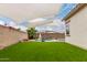 View of the backyard featuring lush green grass, a covered patio, and a sparkling pool with a waterfall feature at 17909 W Agave Rd, Goodyear, AZ 85338
