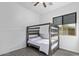Bedroom featuring grey wood bunkbeds with white blankets, a window, and a ceiling fan at 17909 W Agave Rd, Goodyear, AZ 85338