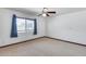 Bright bedroom with neutral carpeting, ceiling fan and large window with blue patterned curtains at 1822 W Marlette Ave, Phoenix, AZ 85015
