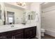 This bathroom features dual sinks, dark wood cabinets, tile floors, and a shower and toilet in the background at 20565 W Terrace Ln, Buckeye, AZ 85396