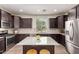 Modern kitchen boasts dark cabinetry, granite countertops, stainless steel appliances, and a center island at 20565 W Terrace Ln, Buckeye, AZ 85396