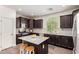 Stylish kitchen featuring dark wood cabinets, stainless steel appliances, a granite island, and tile backsplash at 20565 W Terrace Ln, Buckeye, AZ 85396