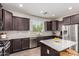 Modern kitchen with a center island, stainless steel appliances, dark wood cabinets, and light tile flooring at 20565 W Terrace Ln, Buckeye, AZ 85396