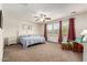 This main bedroom features carpet floors, a ceiling fan, and natural light from the large windows at 20565 W Terrace Ln, Buckeye, AZ 85396