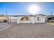 Charming single-story home featuring white exterior, rock landscaping, covered parking, and arched entry at 2508 N 58Th Ln, Phoenix, AZ 85035