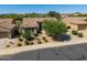 Home's front view showcases a desert landscaped yard, mature trees, and driveway at 4010 E Hamblin Dr, Phoenix, AZ 85050