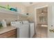 Laundry room with full-sized washer and dryer, storage shelf, and view into the adjacent room at 4010 E Hamblin Dr, Phoenix, AZ 85050