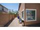 Side yard featuring a graveled area, a gate, a small tree, and the side of the house with a large window at 7274 W State Ave, Glendale, AZ 85303