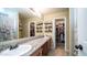 Bathroom featuring double sinks, a large mirror, and access to the walk-in closet at 7274 W State Ave, Glendale, AZ 85303