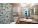 Bathroom with neutral colors, a granite vanity, a cactus-themed shower curtain, and a white cabinet above the toilet at 7274 W State Ave, Glendale, AZ 85303