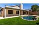 Lush backyard with a kidney-shaped pool, artificial turf, and covered patio area at 8668 N 107Th Dr, Peoria, AZ 85345