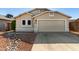 Beige single-story home featuring a two car garage and desert landscaping in front at 8668 N 107Th Dr, Peoria, AZ 85345
