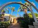Stunning Mediterranean home entrance with archway, tropical palms, and custom double doors at 94 Biltmore Estates Dr, Phoenix, AZ 85016