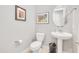 Well-lit powder room with a pedestal sink, round mirror, and artwork creating an inviting space at 23090 S 201St St, Queen Creek, AZ 85142