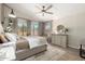 Cozy bedroom with three large windows, a ceiling fan, carpeted floors, a comfortable bed, and simple decor at 10342 E Obispo Ave, Mesa, AZ 85212