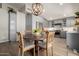 A kitchen with a dining table set in front of grey cabinetry, modern appliances, and a decorative wooden chandelier at 10342 E Obispo Ave, Mesa, AZ 85212