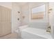 Elegant bathroom with soaking tub, tiled walls, and gold fixtures at 13020 W Highland Ave, Litchfield Park, AZ 85340