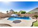 Backyard pool with small waterfall, umbrella, and desert landscaping at 13020 W Highland Ave, Litchfield Park, AZ 85340