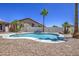 Backyard pool with a unique shape, surrounded by rock landscaping and palm trees against a blue sky at 14039 S 33Rd Way, Phoenix, AZ 85044