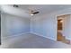 This bedroom features a ceiling fan, neutral walls and carpet, with a glimpse of an adjacent bathroom at 1716 W Villa Theresa Dr, Phoenix, AZ 85023