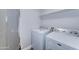 This laundry room is equipped with a washer, dryer, and overhead shelving for storage at 1716 W Villa Theresa Dr, Phoenix, AZ 85023