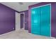 View of a carpeted bedroom showing the accent-colored doors and eye-catching purple paint at 17352 W Red Fox Rd, Surprise, AZ 85387