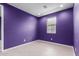 Cozy bedroom with bright white trim, wood-look flooring and a purple accent wall at 17352 W Red Fox Rd, Surprise, AZ 85387