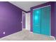 Bedroom with plush carpet and bright-colored walls. Features closet with teal doors and neutral doors leading to ensuite at 17352 W Red Fox Rd, Surprise, AZ 85387