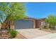 Single-story home with a brick driveway, two-car garage, and flowering tree at 17352 W Red Fox Rd, Surprise, AZ 85387