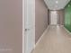 Neutral hallway with sleek tiled floors, and views to a white door and front door at 17352 W Red Fox Rd, Surprise, AZ 85387