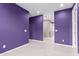 Spacious hallway with modern, light flooring and eye-catching purple paint on the walls at 17352 W Red Fox Rd, Surprise, AZ 85387