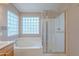 Bright bathroom boasts glass block window, soaking tub, and glass enclosed shower at 20277 N 68Th Dr, Glendale, AZ 85308