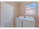A laundry room featuring a washer, dryer, window, and neutral colored walls at 20277 N 68Th Dr, Glendale, AZ 85308