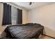 A cozy bedroom features neutral walls, a ceiling fan, and a window dressed with blinds and dark curtains at 2319 N 71St Dr, Phoenix, AZ 85035