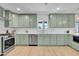 Modern kitchen featuring light green cabinets, stainless steel appliances, and light hardwood floors at 2712 N 20Th Dr, Phoenix, AZ 85009