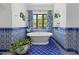 Bright bathroom featuring blue and white tile accents, a modern soaking tub, and natural light at 5225 N 23Rd St, Phoenix, AZ 85016