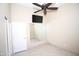 Bedroom with tan walls features ceiling fan, TV, a mirror, and neutral tile flooring at 5437 W Bluefield Ave, Glendale, AZ 85308
