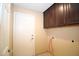 Laundry room featuring utility sink, upper cabinets, exterior door, and tile flooring at 5437 W Bluefield Ave, Glendale, AZ 85308