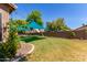 Grassy backyard features shade sails, mature landscaping, and a fenced perimeter for added privacy at 557 S Lemon Ct, Gilbert, AZ 85296