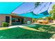 Well-maintained backyard showcasing a covered patio with outdoor grill, a play structure, and ample green space for recreation at 557 S Lemon Ct, Gilbert, AZ 85296