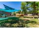 Large backyard with a wooden deck, shade sail, lush lawn, offering a great space for outdoor activities at 557 S Lemon Ct, Gilbert, AZ 85296