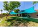 Expansive backyard featuring a lush lawn, mature trees, and a stylish shade sail-covered patio area perfect for outdoor entertaining at 557 S Lemon Ct, Gilbert, AZ 85296