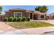 Manicured front yard featuring green grass, trimmed bushes, decorative rocks, and a quaint brick border at 557 S Lemon Ct, Gilbert, AZ 85296