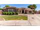 Landscaped front yard featuring green lawn, manicured shrubbery, and a concrete driveway leading to the garage at 557 S Lemon Ct, Gilbert, AZ 85296