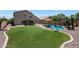 Manicured backyard with sparkling pool, lush green grass, and lounge chairs at 5744 E Jacaranda St, Mesa, AZ 85205