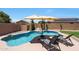 Backyard pool featuring a waterfall, lounge chairs and a large umbrella for shade at 5744 E Jacaranda St, Mesa, AZ 85205