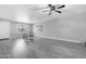 Spacious living room with modern floors, ceiling fan, and bright window lighting at 5813 W Gelding Dr, Glendale, AZ 85306
