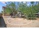 Backyard featuring a playset area with a slide, mature trees, and gravel landscaping at 9912 W Illini St, Tolleson, AZ 85353