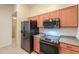 Kitchen with black appliances, wood cabinets, and tile floors; offers great flow and functionality at 1336 E Laurel Pl, Casa Grande, AZ 85122